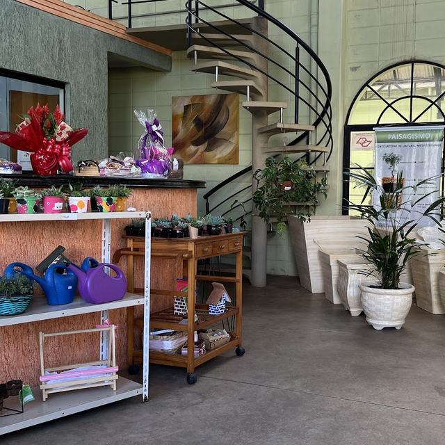Balcão com regadores, vasinhos e arranjos, ao lado da escada caracol